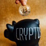 person putting bitcoin in a piggy bank